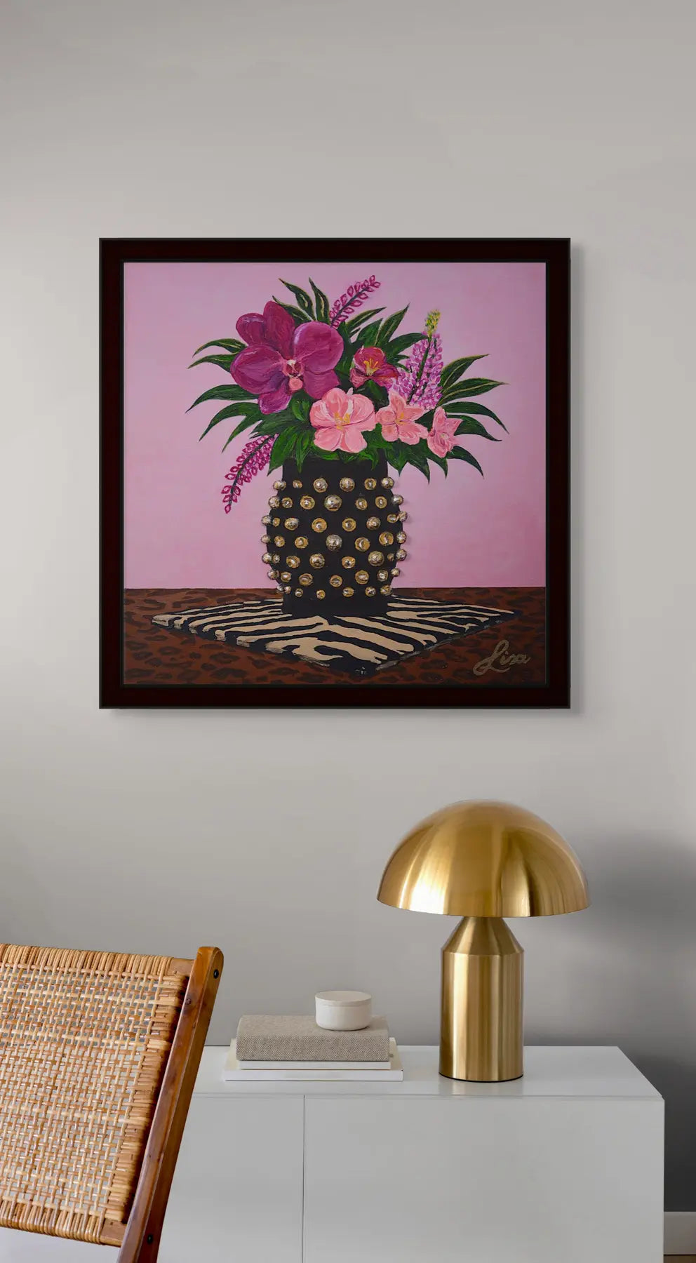 Original floral painting styled with a black frame and gold accent lamp in a curated interior.