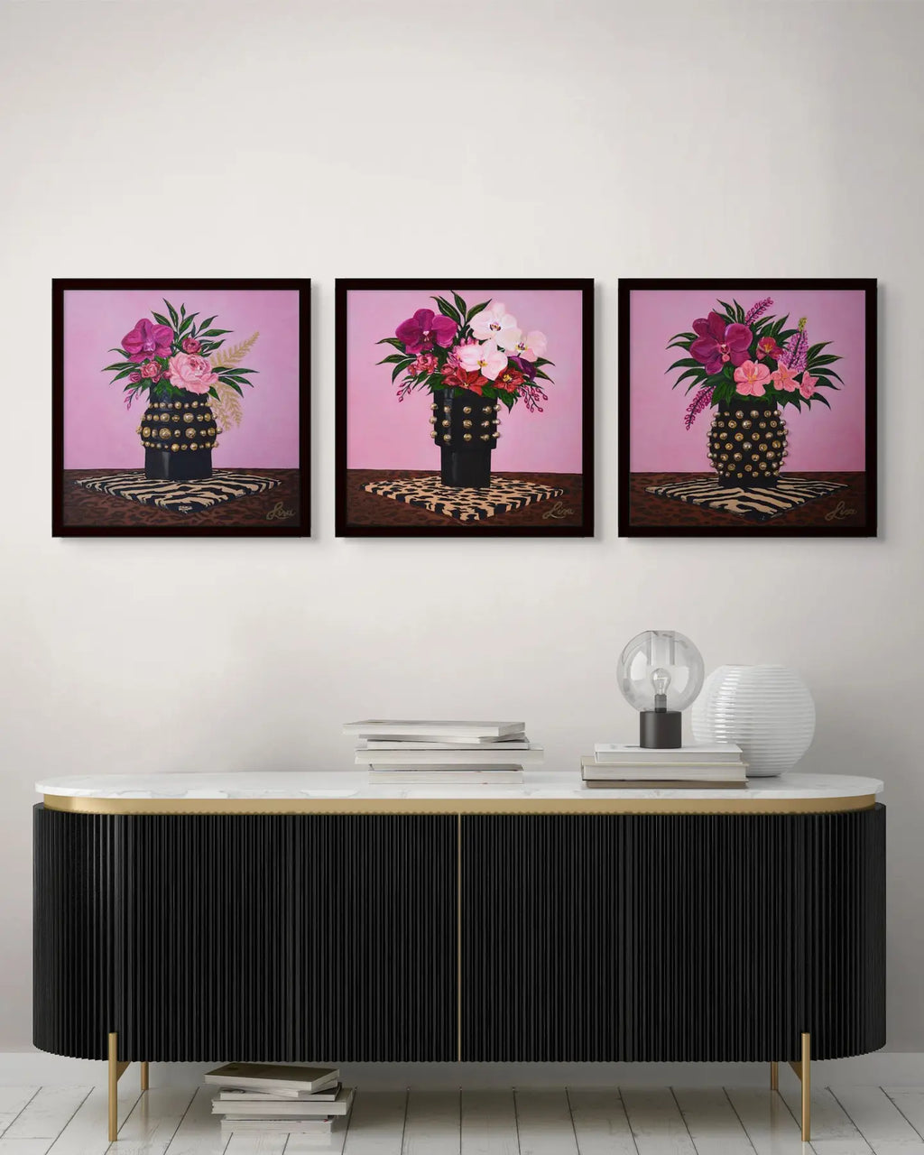 Original floral triptych paintings framed in black and styled above a modern console.